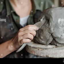 A sculptor forming clay into a defined shape.