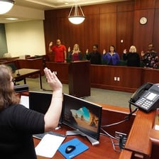 A courtroom scene with a judge, attorneys, and a jury.