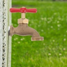 A metal outdoor water spigot attached to a wall