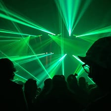 A crowded rave illuminated by vivid green lights.