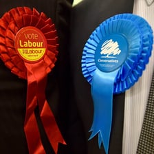 A Conservative Party rosette representing a Tory, with its first half used as the letters TO.