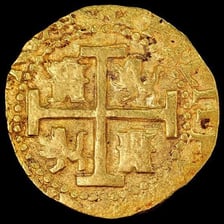 An old Spanish real coin shown as a historical currency object.