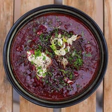 A bowl of red beetroot borscht garnished with sour cream.