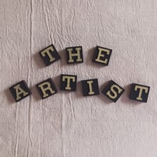 Letter tiles showing NICE ART rearranged to spell CERTAIN.