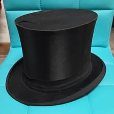 A collapsible black opera hat shown partly folded.