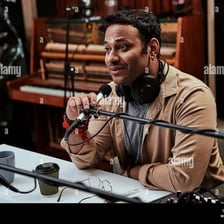 A radio announcer speaking into a microphone at the start of a broadcast
