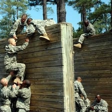 People tackling obstacles on an outdoor assault course.