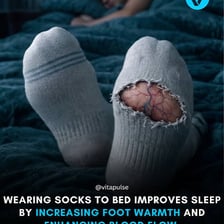 A bed at night with a pair of warm socks nearby