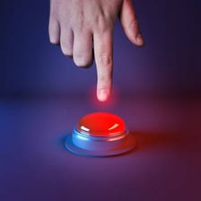 A finger poised on a red push button.