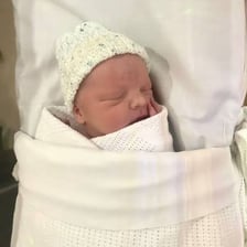 A newborn baby being held in a maternity ward.