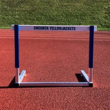 Athletes sprinting over hurdles on a track.