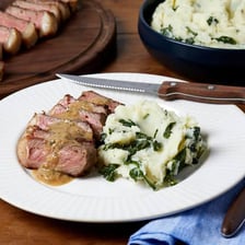 A plate of meat served with potatoes