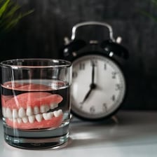 A set of dentures resting in a glass of water.