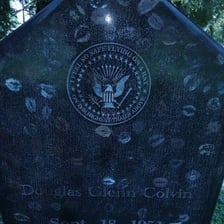 An eagle flying above a stone gravemarker.