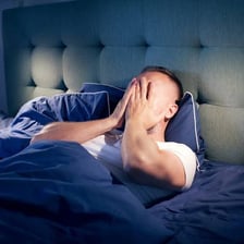 A person awake in bed at night, unable to sleep