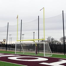 A football goalpost standing upright on a soccer pitch.