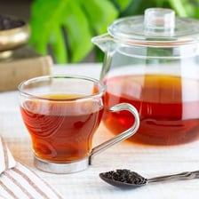 A cup of Assam tea beside loose tea leaves