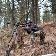 A hunter carrying a rifle in woodland