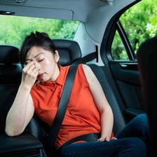 A passenger appearing unwell from motion sickness inside a car