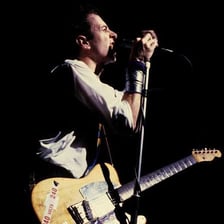 Joe Strummer performing with an electric guitar.