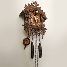 A traditional wooden cuckoo clock with its clock face and pendulum.
