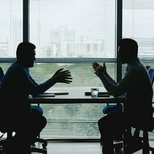 Two people reaching an agreement across a negotiating table.