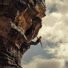 A dramatic scene of a climber on a steep mountain face.