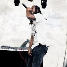 A rap musician performing into a microphone on stage.