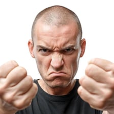 A person visibly expressing anger with a tense expression and clenched fists.
