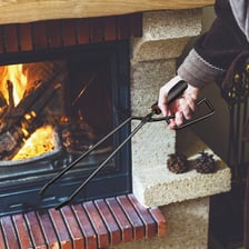 Metal fireplace tongs being used to handle hot coals