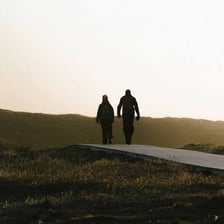 A person walking across a landscape between distant locations