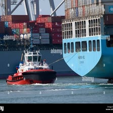 A small tugboat maneuvering beside a larger vessel