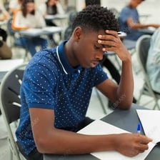 A student completing a written exam in a classroom.