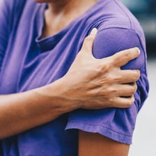 A person holding an area of the body affected by pain