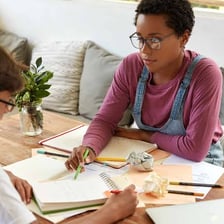 A student working with a tutor at a desk