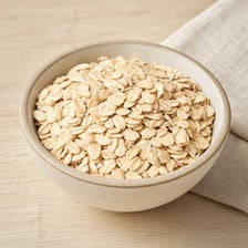 A bowl of oatmeal beside loose oat grains.