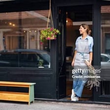 A person standing outside a shop they own