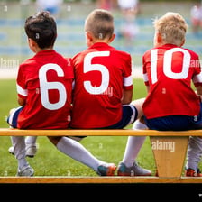 A substitute soccer player seated on the team bench.