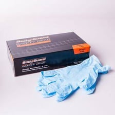 A container of lye cleaning solution beside protective gloves.