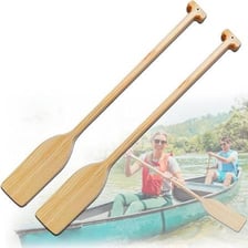 A wooden rowing oar beside a small boat