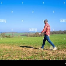 A lone person walking across an open rural landscape