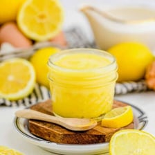 A jar of lemon curd beside fresh lemons