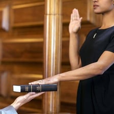 A person raising a hand while taking an oath