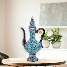 An ornate ceramic ewer with a handle and pouring spout.