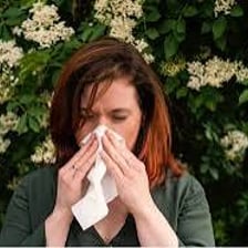A person sneezing outdoors during pollen season