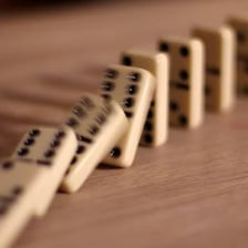 A line of dominoes falling in succession, one after another.