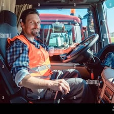 A lorry driver seated in the cab of a heavy goods vehicle