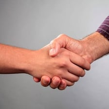 Two people shaking hands as one gives a recommendation