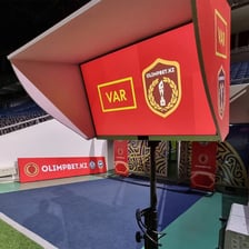 A football match with a referee consulting a VAR monitor.