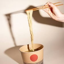 A single ramen noodle strand held with chopsticks